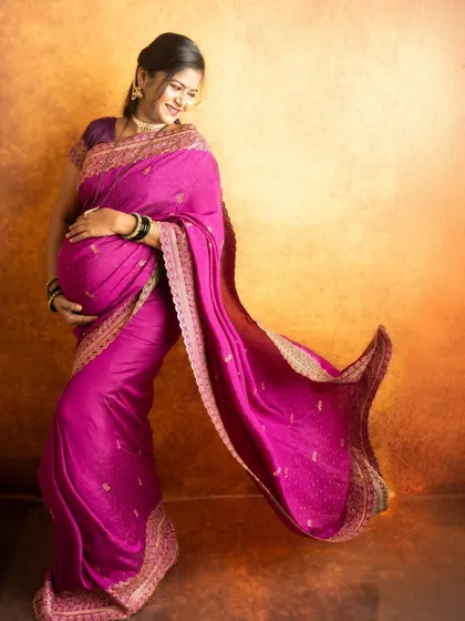 A dynamic shot of a flowing pink saree against a warm, textured backdrop. The movement in the fabric adds a touch of grace and energy.