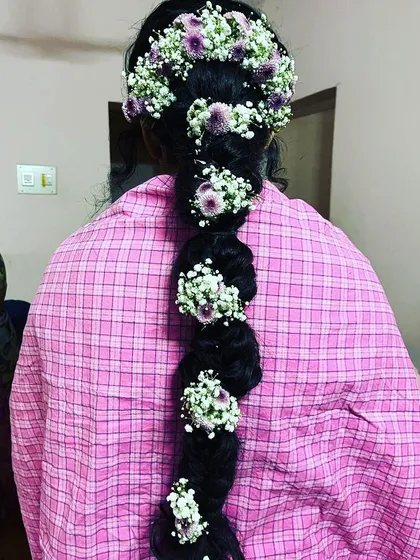 I also specialize in traditional hairstyling. This is a classic South Indian braid, intricately woven and adorned with fresh baby's breath and purple flowers, a popular choice for weddings and religious ceremonies.