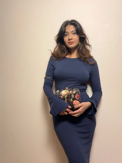 The clutch paired with a sleek navy dress. The floral print on the bag adds a lovely contrast to the solid color of the dress.