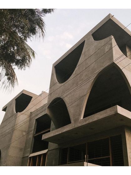 A villa under construction, revealing its bold concrete form. The design features dramatic arches and voids that will eventually be softened by glass and landscaping.