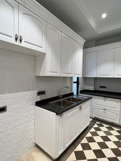 A bright and clean Victorian-style kitchen at our C-257 project. The white cabinets, dark granite countertops, and checkerboard floor create a timeless and appealing look.