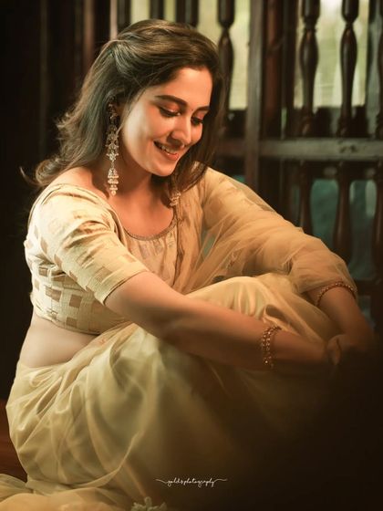 Soft, candid-style portraits of an actress in a simple cream-colored saree. The warm, diffused lighting and relaxed pose create an intimate and gentle mood.