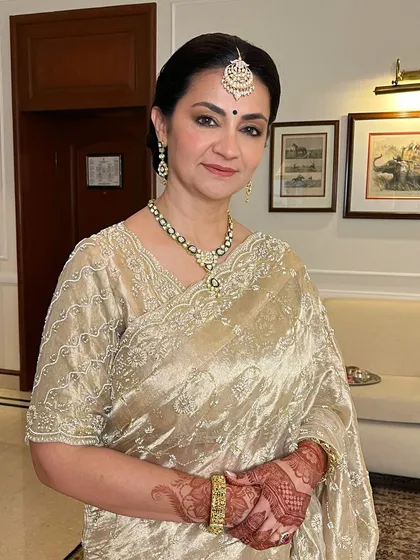 A portrait of pure grace. This mother of the bride's makeup is soft and luminous, perfectly complementing her gold saree and elegant jewelry.