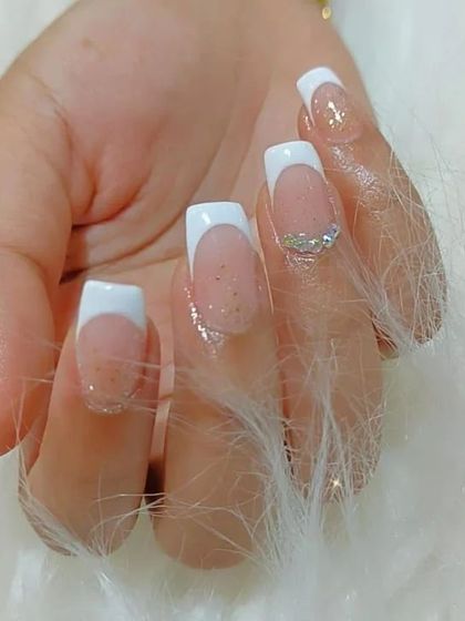 A close-up of a classic French manicure on square nails, enhanced with a subtle glitter base and a single rhinestone accent.