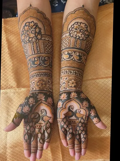 A stunning engagement mehendi with peacocks on the palms and basket-like motifs on the arms.