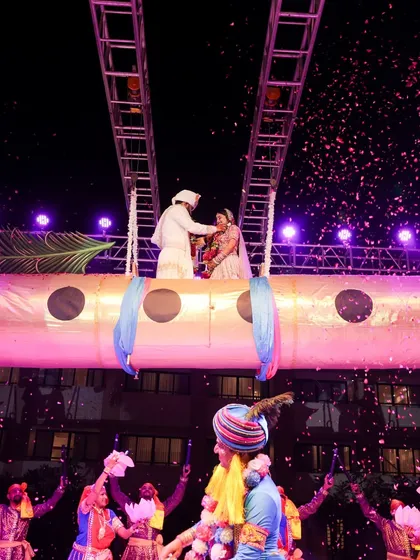 A unique and theatrical varmala, where the couple is elevated on a stage designed like a giant flute, a nod to the Radha-Krishna theme of the event.