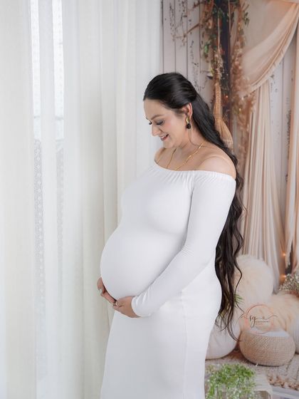 A serene and beautiful profile shot by the window. The natural light softly illuminates the mother-to-be, highlighting her gentle glow.