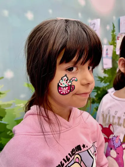 Getting into the holiday spirit with a festive hot cocoa design on the cheek. This is a great example of detailed cheek art that adds a touch of Christmas magic to any event.