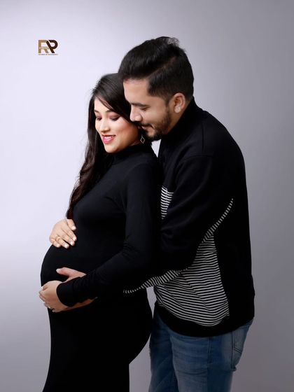 An intimate and classic maternity pose. The couple is dressed in black, creating a timeless look that puts all the focus on their connection and the baby bump.