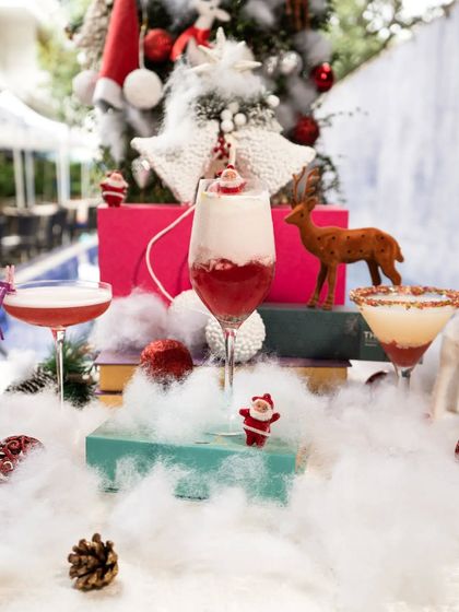 A festive display of our exclusive Christmas cocktails. We craft delightful blends of seasonal flavors, like this layered red drink, to help you celebrate the holiday season in style.