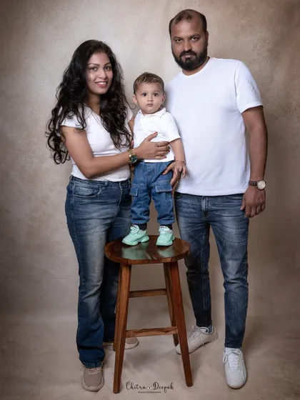 A classic studio family portrait with parents and their young child, coordinated in timeless white shirts and jeans. This demonstrates our style for creating clean, simple, and elegant family pictures.