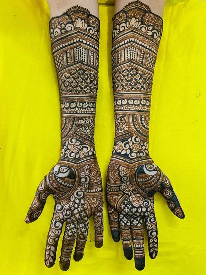 A gorgeous bridal design featuring heart-shaped peacock motifs on the palms. The arms are adorned with architectural patterns and delicate florals, creating a romantic and intricate look.