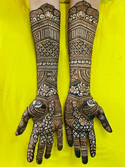 A gorgeous bridal design featuring heart-shaped peacock motifs on the palms. The arms are adorned with architectural patterns and delicate florals, creating a romantic and intricate look.