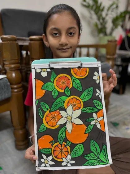 A student displays her intricate orange-themed artwork. This piece shows advanced skills in pattern work and composition, perfect for teens looking to build their portfolio.