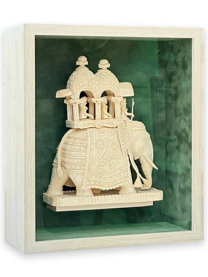 This front-on view highlights the intricate details of the Sholapith elephant against a pine suede matboard. The shadow box construction gives the piece dimension, making it feel like a museum exhibit.