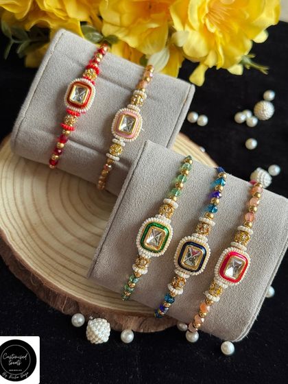 A collection of square kundan rakhis with colorful enamel borders. The combination of traditional kundan work with modern shapes makes these rakhis unique.