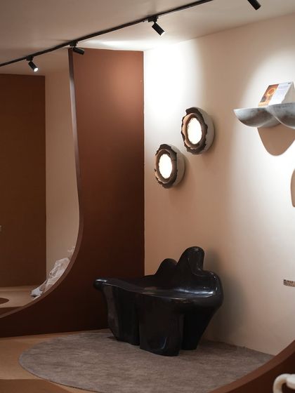 Another shot of our exhibition space, highlighting the interplay between our sculptural furniture and lighting. The dark coral bench and glowing wall sconces create a moody and sophisticated atmosphere.