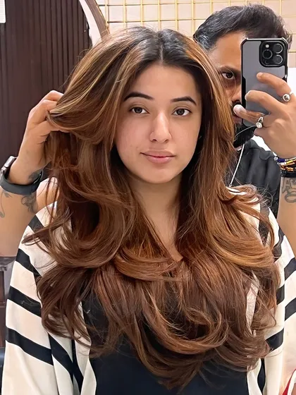 A client showing off her new "Millionaire" haircut. The layers are styled to create maximum volume and a glamorous, windswept look.