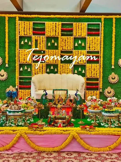 Color and tradition come together in this vibrant baby shower setup. The backdrop, inspired by a woven pattern with marigolds and green leaves, creates a cheerful and auspicious atmosphere for the celebration.