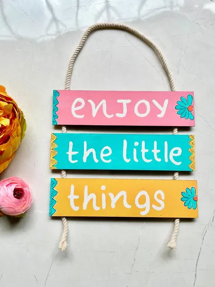 'Enjoy the little things'. A sweet and simple message on a colorful, hand-painted wall hanging.