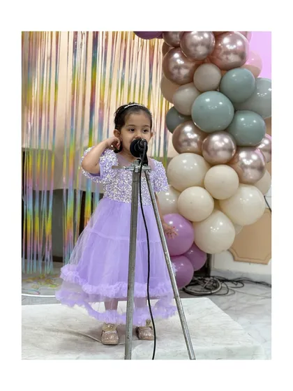 A little princess in a beautiful lavender dress, singing her heart out.
