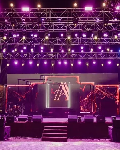 The concert-style stage setup for the Sangeet night. The powerful lighting rig and large LED screen with the couple's monogram ensured a high-energy, unforgettable party.