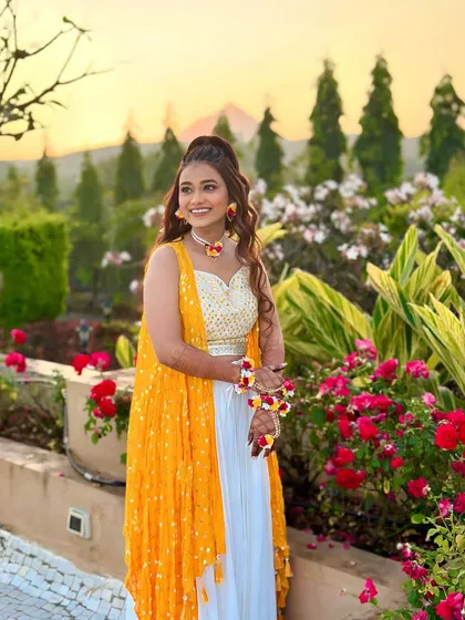 This bride's Haldi look has us swooning. The white and yellow outfit is fresh and modern, paired with beautiful floral jewellery and a radiant smile.