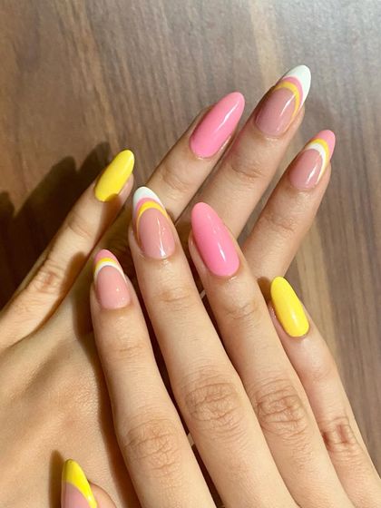 A bright and cheerful set with a mix of solid pink and yellow nails and abstract French tips.