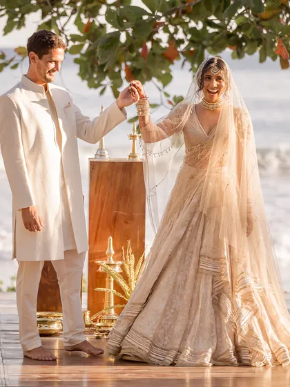 A joyful dance on the deck overlooking the ocean. Their coordinated ivory wedding attire looks light, elegant, and perfect for the beach setting.