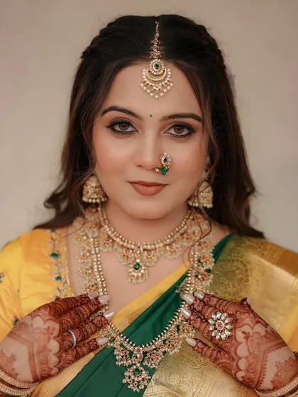 A close-up of a glowing Maharashtrian bride in a yellow and green saree. Her look features defined eyes, traditional jewelry, and a beautiful nath.