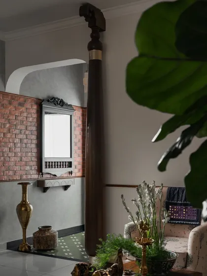 First impressions matter, and the foyer of our 'Kaalam' project sets a tone of rooted tradition. A reclaimed wooden sthamba (pillar) stands as a proud centerpiece, complemented by the rustic texture of an exposed brick wall and a vintage-inspired mirror. This entry is a deliberate nod to the past, reinterpreted for a modern home.
