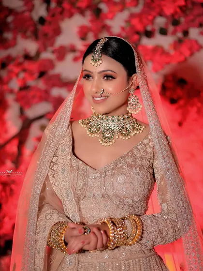 A portrait of the bride against a vibrant red floral background, which makes her pastel lehenga stand out.