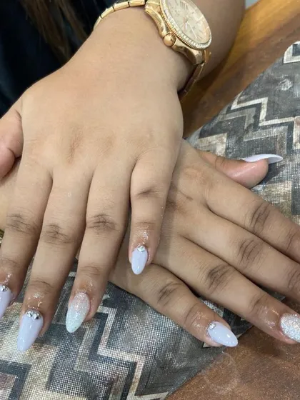 Icy and elegant. These almond-shaped nail extensions are done in a cool, light blue shade with a subtle glitter accent nail and a few perfectly placed rhinestones at the cuticle for a clean, polished look.