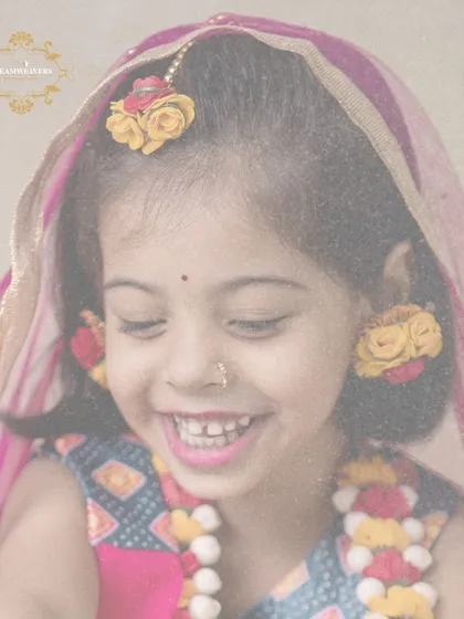 A close-up of a smiling girl dressed as Radha, with beautiful floral jewelry. Her genuine happiness shines through in this portrait.