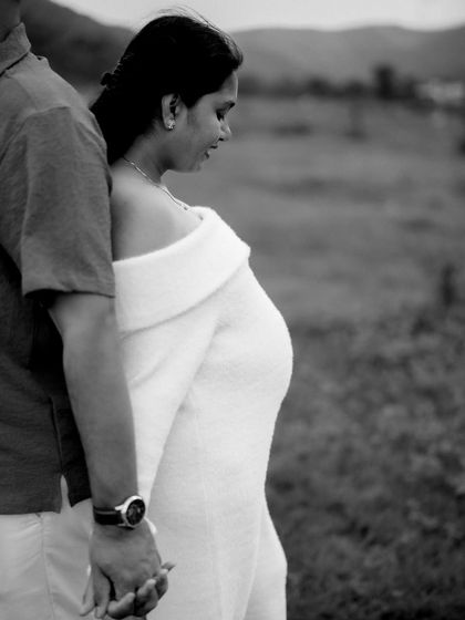 A beautifully composed black and white shot. The couple holds hands, standing close together, creating a sense of unity and quiet strength.