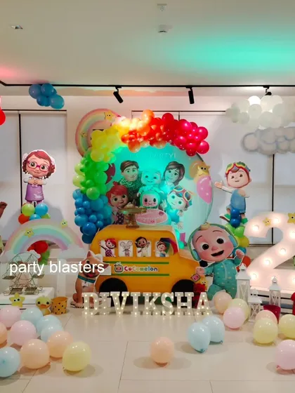 A wide shot of the entire Cocomelon setup, showing how all the elements, from the rainbow balloon arch to the character props, come together to create a joyful and colorful party scene.