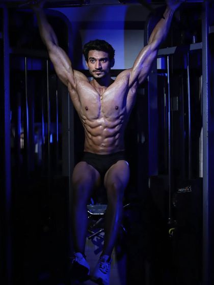 An abs and thigh pose, hanging from a pull-up bar. This demonstrates core strength and a lean, defined midsection.