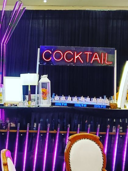 A vibrant cocktail bar setup with purple LED lighting and multiple neon signs for a fun, party-ready look.