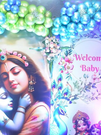 This "Welcome Baby" backdrop was designed for a naming ceremony with a Krishna theme. The beautiful image of Yashoda and Krishna is framed by a vibrant blue, green, and gold balloon arch.