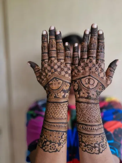 A full view of the engagement mehendi, showing the date on one palm and interlocking rings on the other, with a beautiful floral cuff.