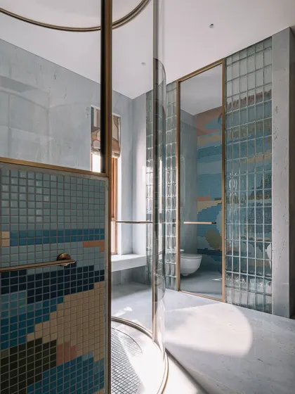 We believe bathrooms should be an escape. This master bathroom features a unique cylindrical shower cubicle, where a playful dance of colorful mosaic tiles and glass blocks creates a space that feels both luxurious and deeply personal.