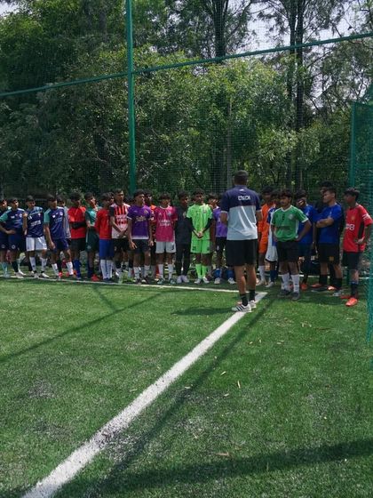 A coach addresses a large group of trialists for the U16 and U18 squads, outlining the day's schedule and what is expected of them.