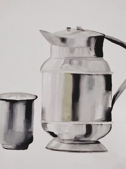 A finished student piece showing a steel jug and glass. This monochrome study focuses purely on capturing form and reflection using different shades of grey, a core tonal exercise.
