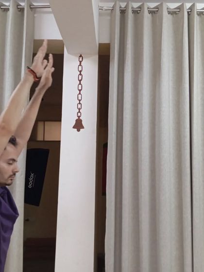 A participant reaches upwards, lengthening the spine as part of the Surya Kriya sequence.