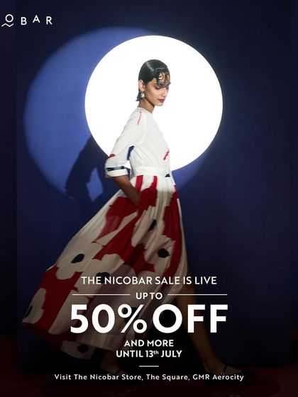 An artistic shot announcing the Nicobar sale, featuring a model in a flowing dress with a bold floral print. It captures the brand's blend of art and fashion.