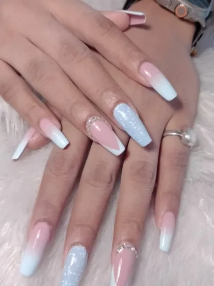 A dreamy "frozen" look with long coffin nails featuring a pink and blue ombre, with glitter and rhinestone accents.