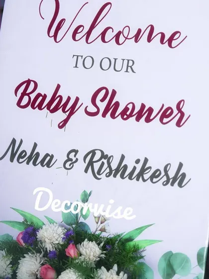 A simple yet elegant welcome sign for Neha and Rishikesh's baby shower. The clean typography and subtle floral graphic at the bottom provide a clear and heartfelt welcome to the celebration.