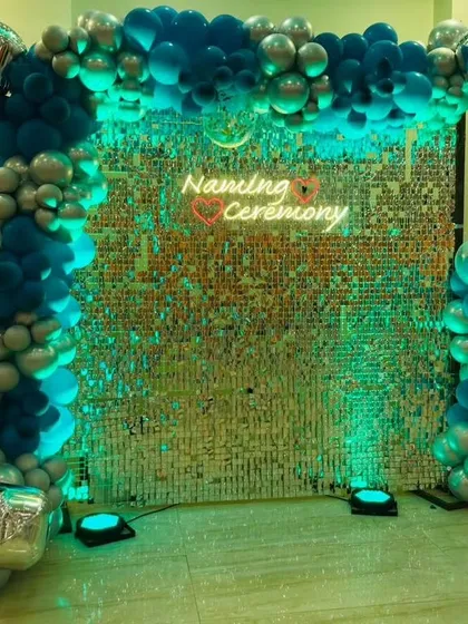 A shimmering sequin wall makes a fantastic photo backdrop for any modern celebration. For this naming ceremony, I framed the wall with a blue and silver organic balloon garland and added a custom neon sign to mark the special occasion.