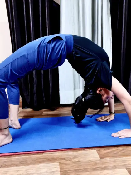 A student demonstrates a beautiful Chakrasana (Wheel Pose). This deep backbend is excellent for spinal flexibility, strengthening the arms and legs, and opening the chest to improve breathing.