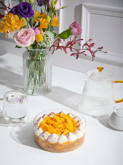 Our Mango Tres Leches, perfect for sharing, set on a table with fresh flowers.